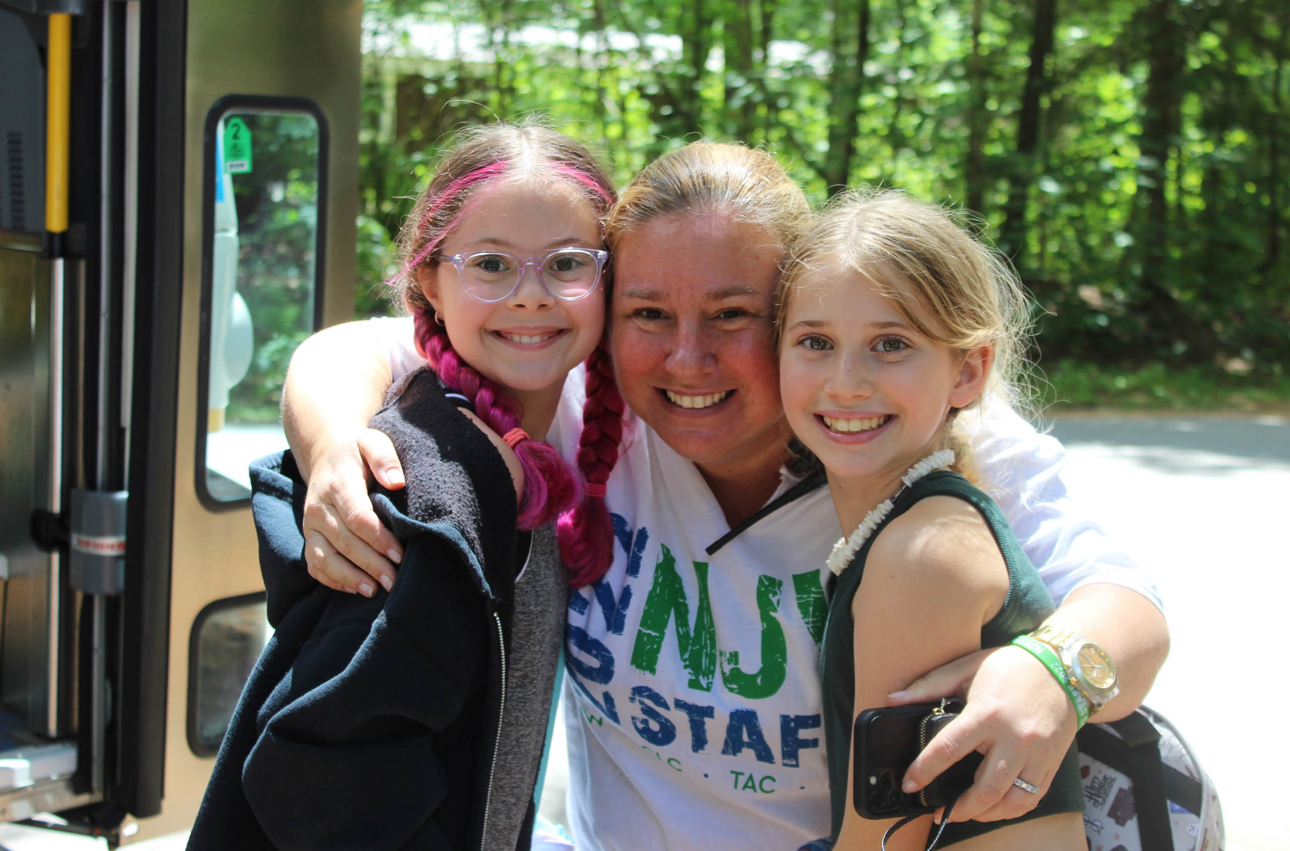 A staff member welcoming two campers.