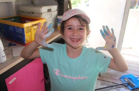 A camper with paint on her hands.