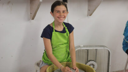 A camper working on ceramics on a wheel.