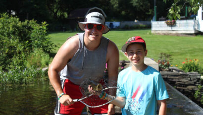A staff member and camper fishing.