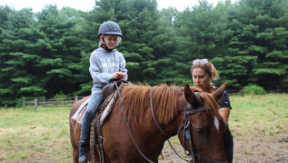A camper learning to horseback ride.