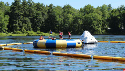 Campers on an inflatable obstacle on a lake.