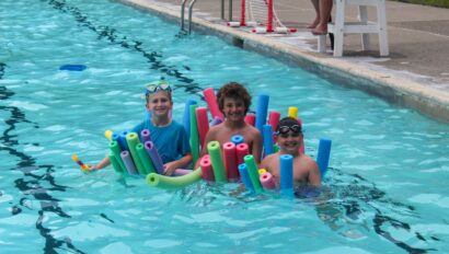 Three campers with pool noodles.