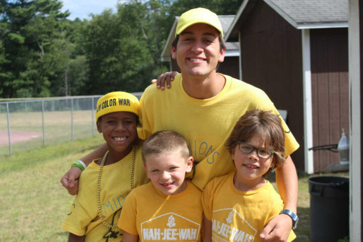A staff member and three campers smiling.