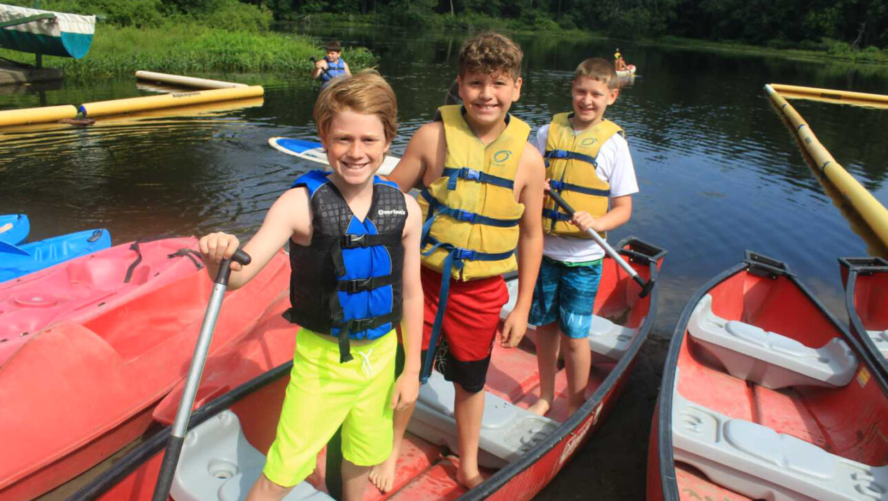 Three campers ready to go canoeing.