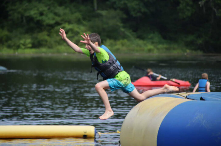 A boy jumping on inflatable lake elements.