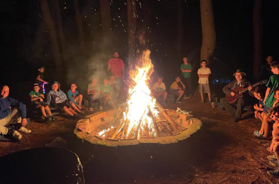 Campers gathered around a camp fire.